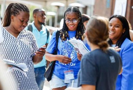 Three students talk to another while visiting a table at the D I C E Resource fair.